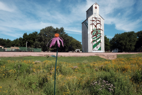 Prairie flowers bloom in front of a metal sculpture adorning a grain elevator at Woodbine's entrance. Photo courtesy of Sandra Oberbroeckling/Iowa State University.