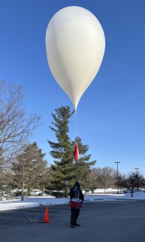 A student holds a fully inflated high-altitude balloon and prepares to release it
